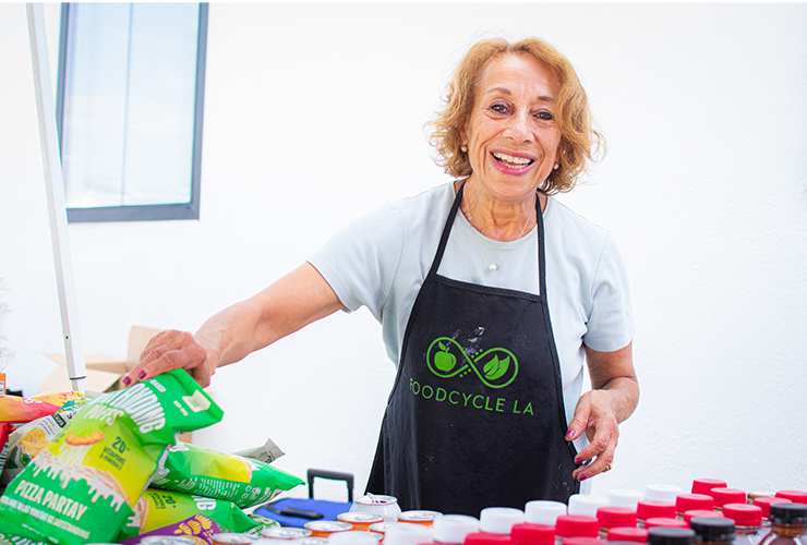 a woman in a green apron standing behind a table